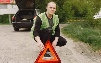 Driver putting warning triangle on asphalt road. Emergency stop concept.